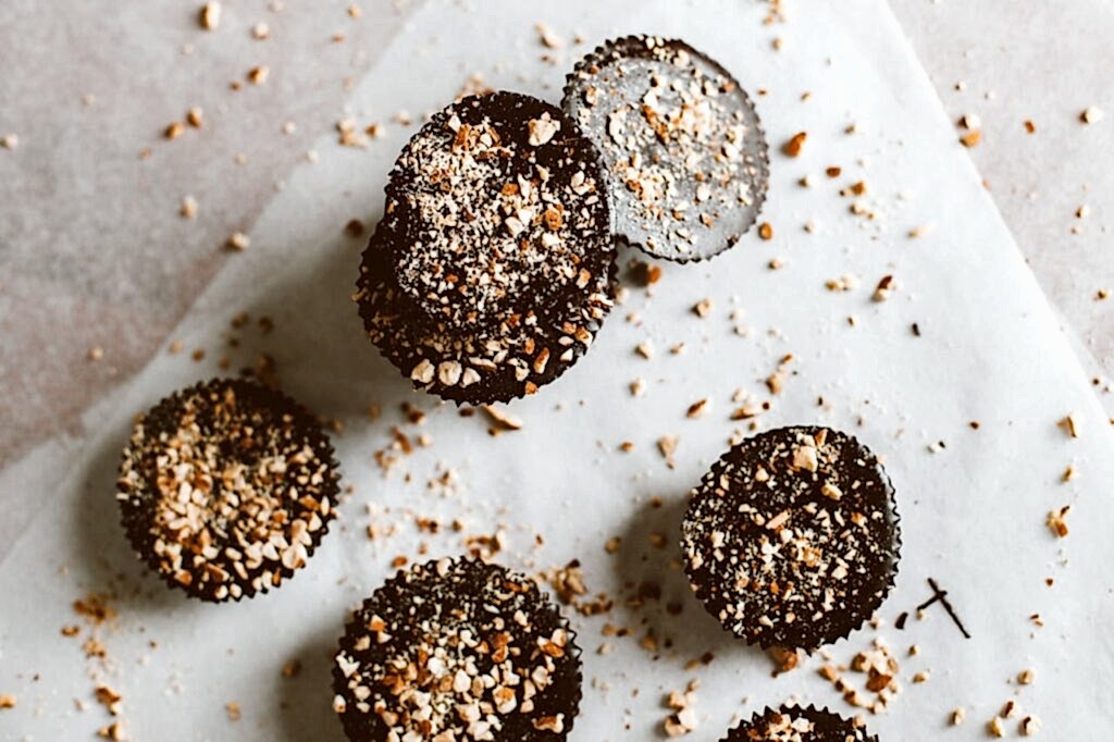 Top view of dark chocolate bites sprinkled with almonds on parchment paper.